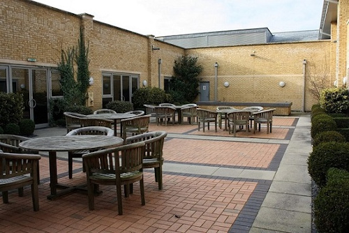 Alexandra House Hotel - One of the courtyards with wooden tables, chairs and parasols
